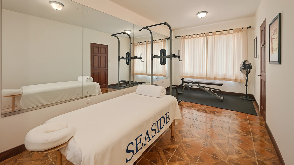 Private wellness suite with massage area, gym equipment and free-weights.